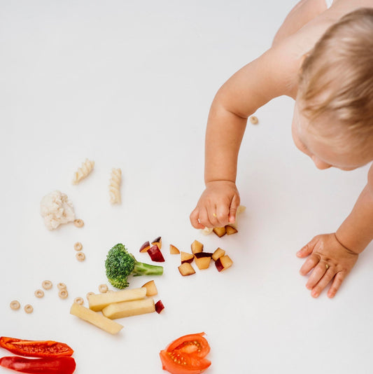 Bambino che gioca e prende piccoli pezzi di frutta e verdura