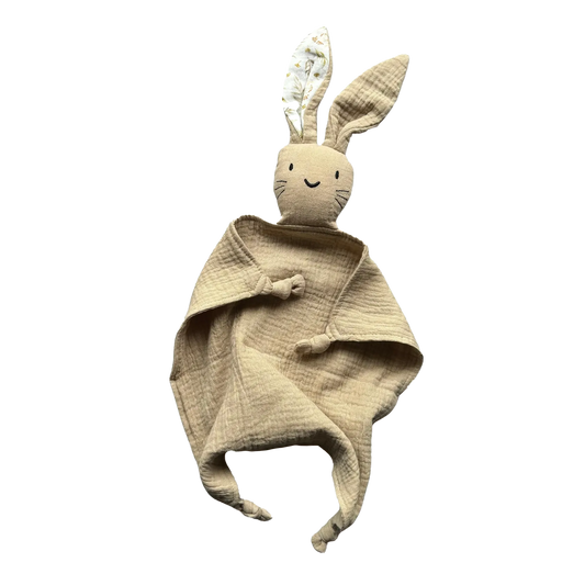 Doudou coniglietto in mussola di cotone 100% –Il primo amico del tuo bambino. Beige Biscotto- tenero e avvolgente
realizzato in mussola di cotone 100%
Il tessuto leggero e traspirante dona comfort e sicurezza, mentre le orecchie da coniglietto e i nodi agli angoli stimolano il tatto e invitano alla scoperta.
Ideale  per accompagnare il sonno e offrire conforto nei momenti
Lavabile in lavatrice
Prodotto sicuro, conforme agli standard per neonati. Certificazione CE Sacchetto regalo ecologico in cottone
